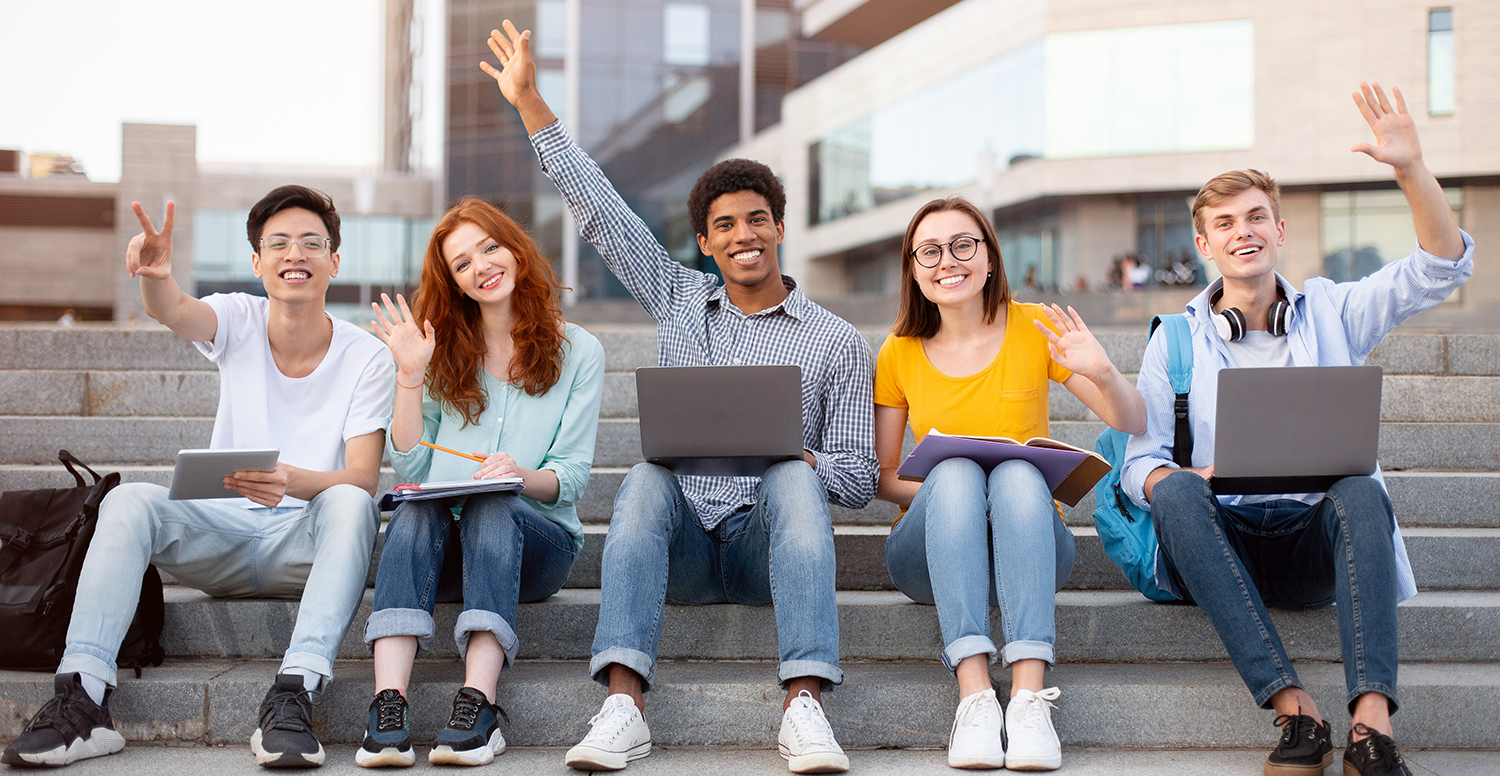 Multiracial students raising hands in the air and waving.