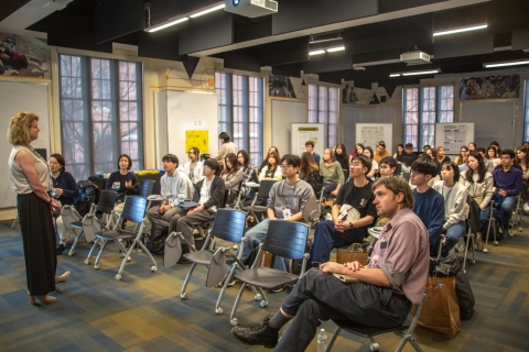 Students sit in a classroom while a presenter speaks at the front; Collin Delargy, Assistant Director of Housing Innovation Lab for the City of Atlanta, sits in the front row listens alongside the group.